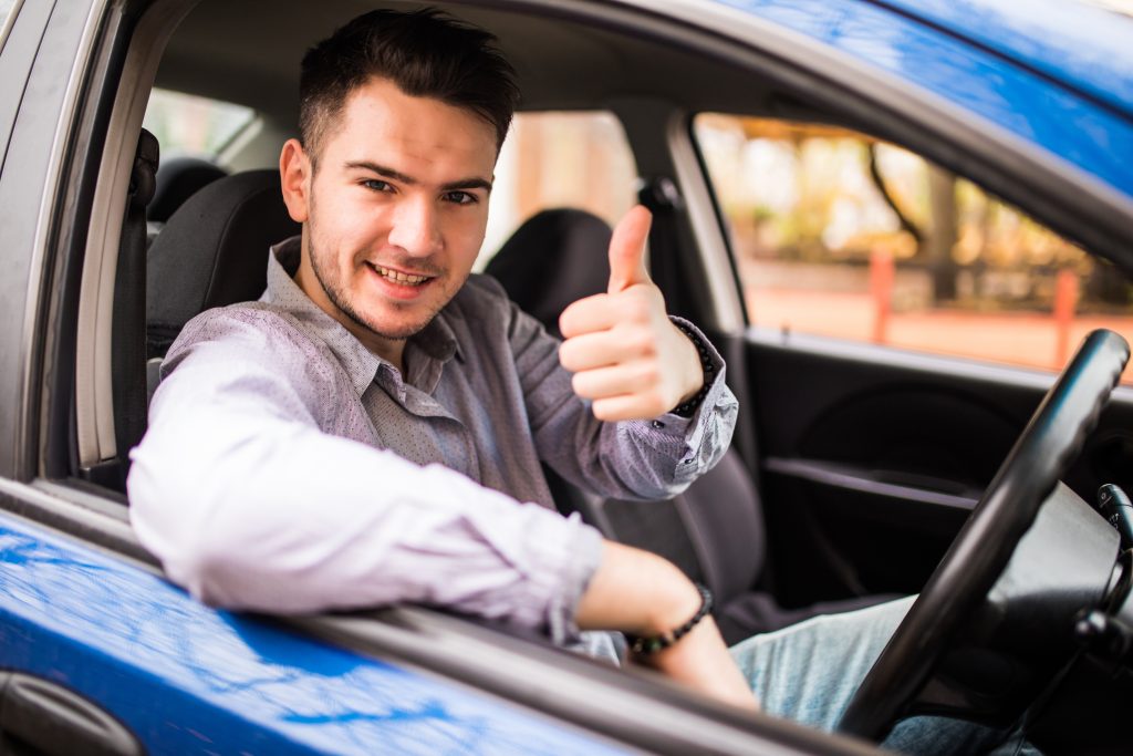 A young male driver gives the thumbs up